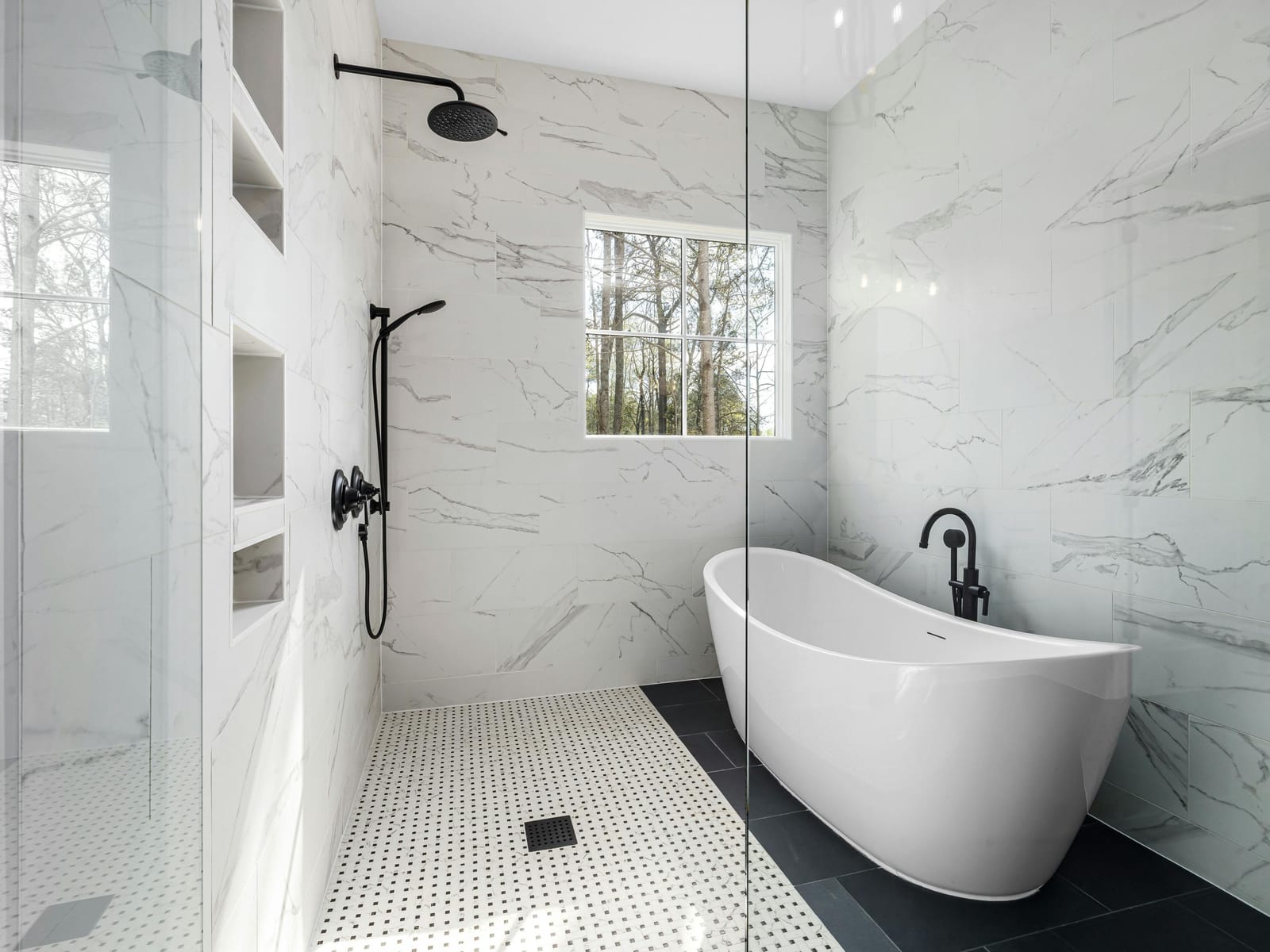 Finished bathroom renovation with marble tile, a freestanding tub, and a glass-enclosed shower with black fixtures