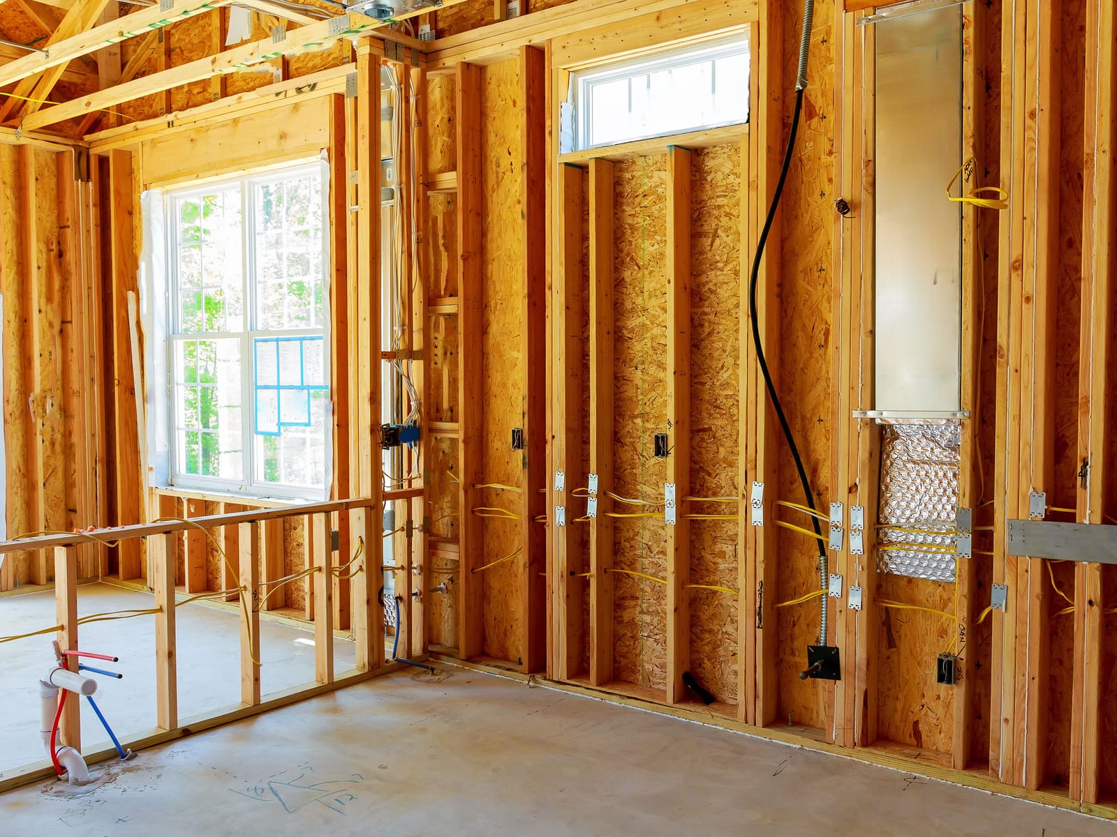 Electrical rough-in wiring and outlet boxes running through stud wall framing on a renovation