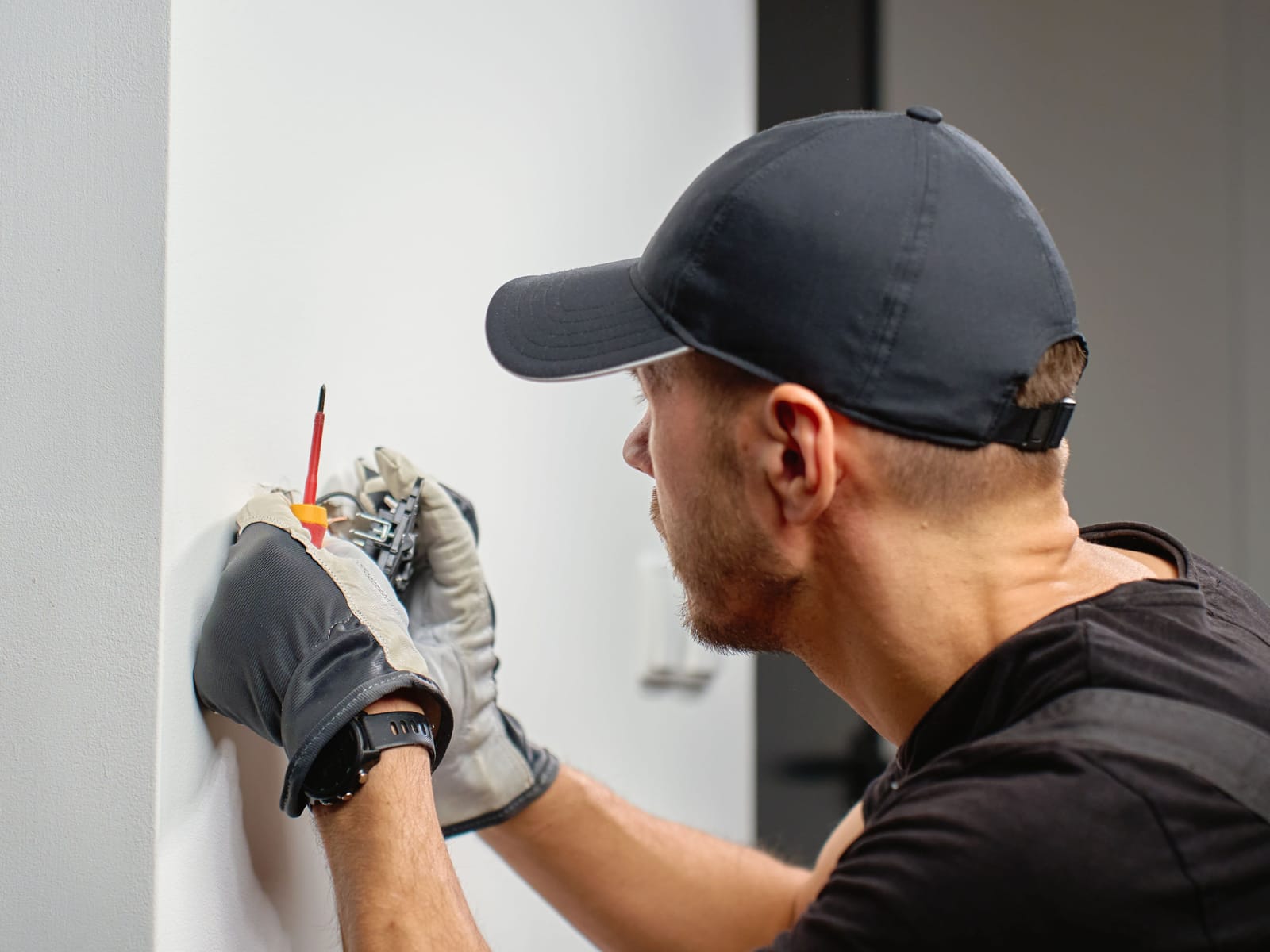 Rytek Construction electrician installing an electrical device in a finished wall