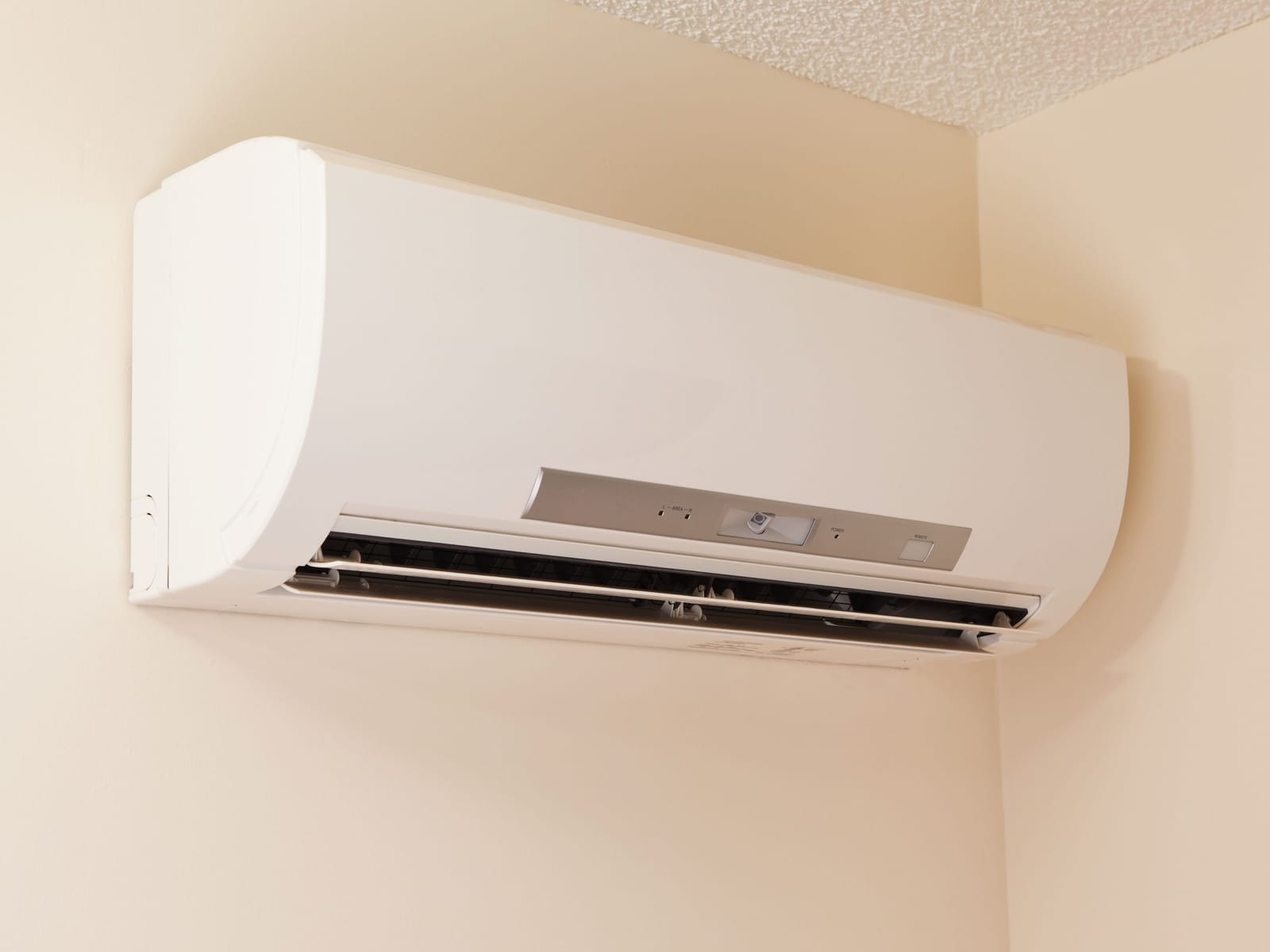 Wall-mounted ductless mini-split heat pump head installed in the corner of a finished room
