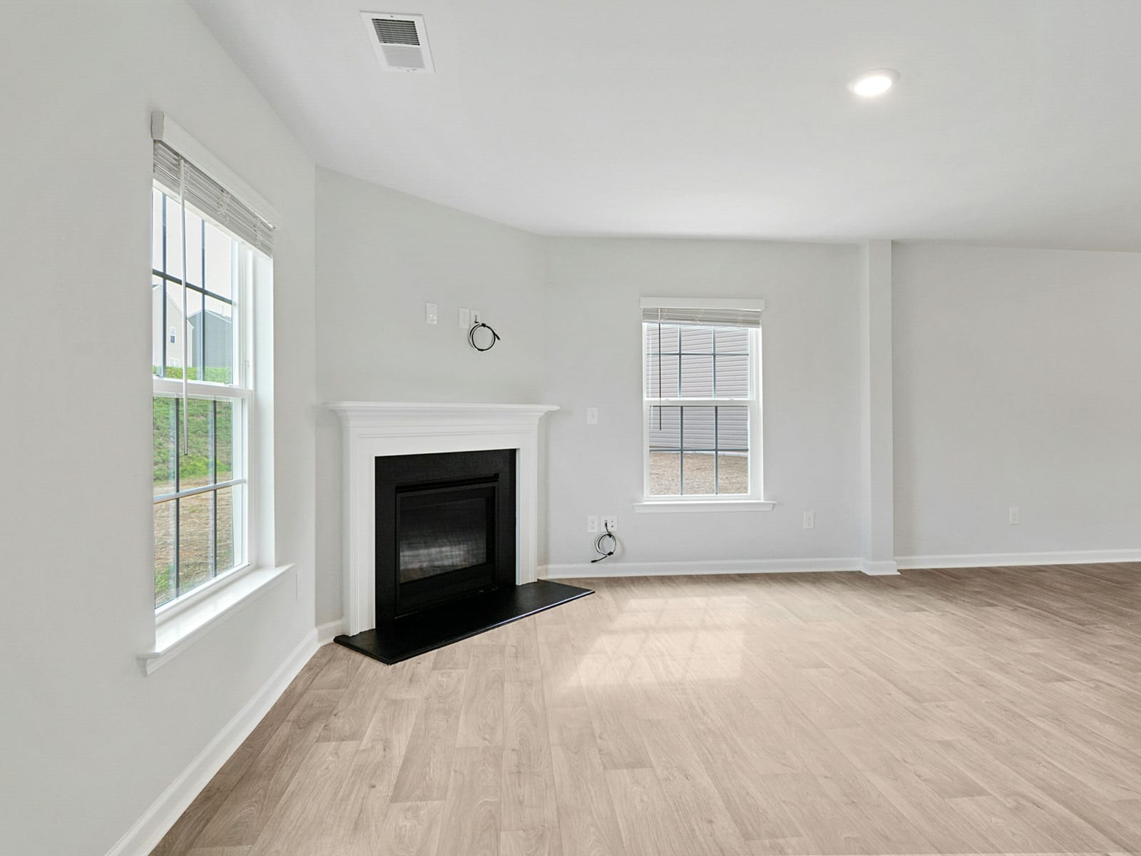 Freshly painted living room with soft grey walls, white trim, and a white fireplace mantel